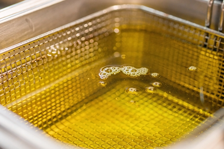 Close-up van heldere frituurolie in een professionele friteuse tijdens het bakken